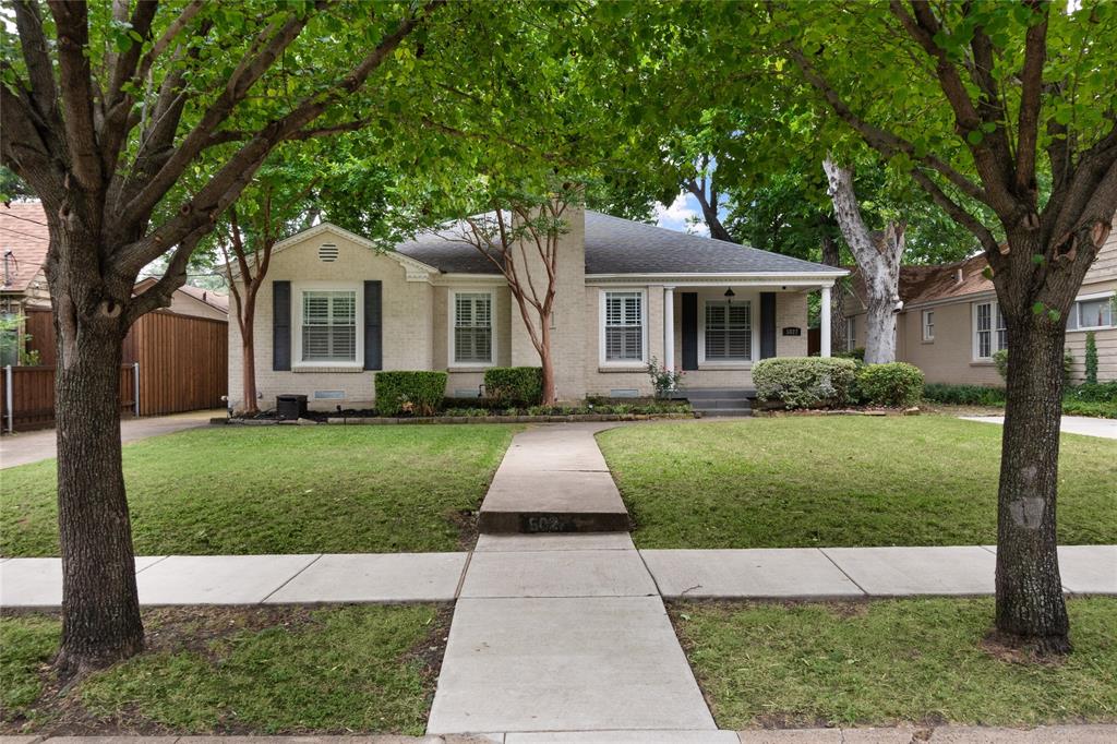 a front view of a house with a garden and trees