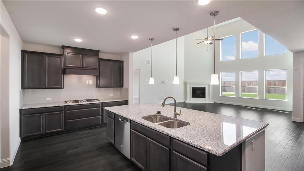 a kitchen with stainless steel appliances granite countertop a sink a stove and kitchen island with wooden floor