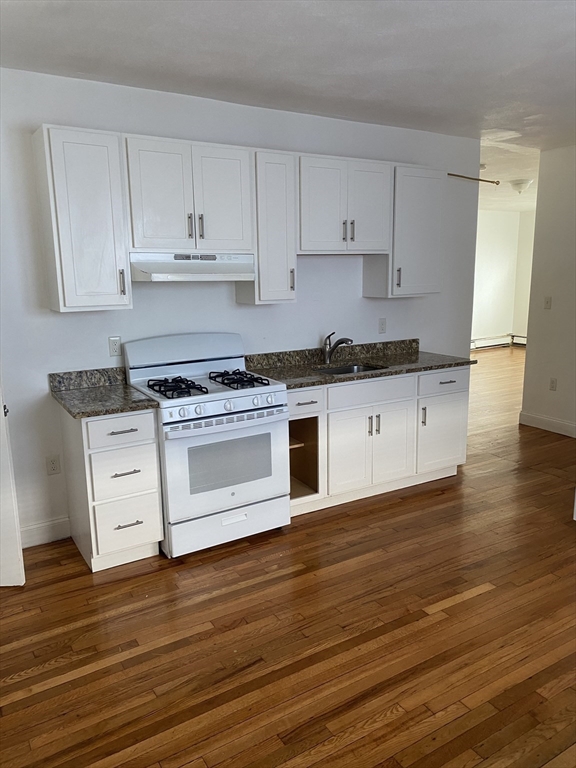 a kitchen with granite countertop wooden floor stainless steel appliances and cabinets