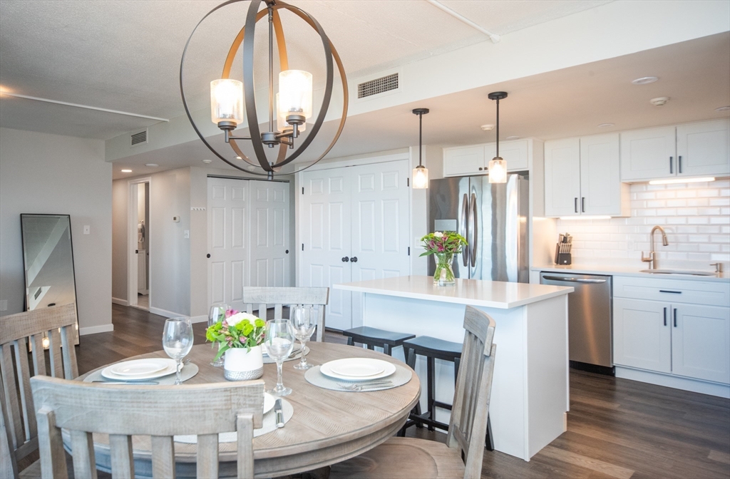 a kitchen with stainless steel appliances kitchen island granite countertop a table chairs and a chandelier