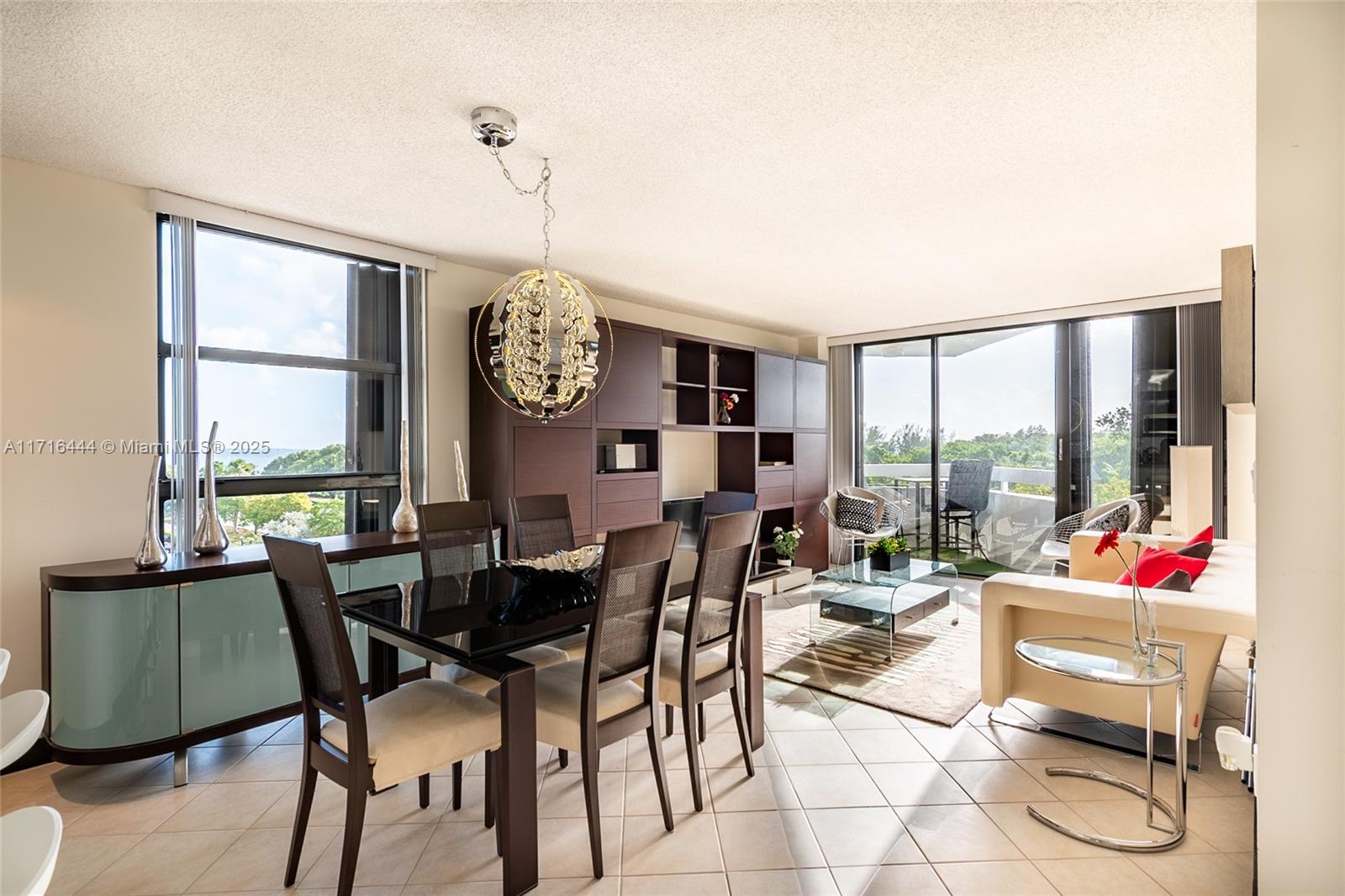 a dining room with furniture large windows and a chandelier