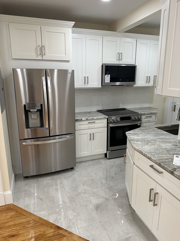 a kitchen with stainless steel appliances granite countertop a stove a refrigerator and a microwave