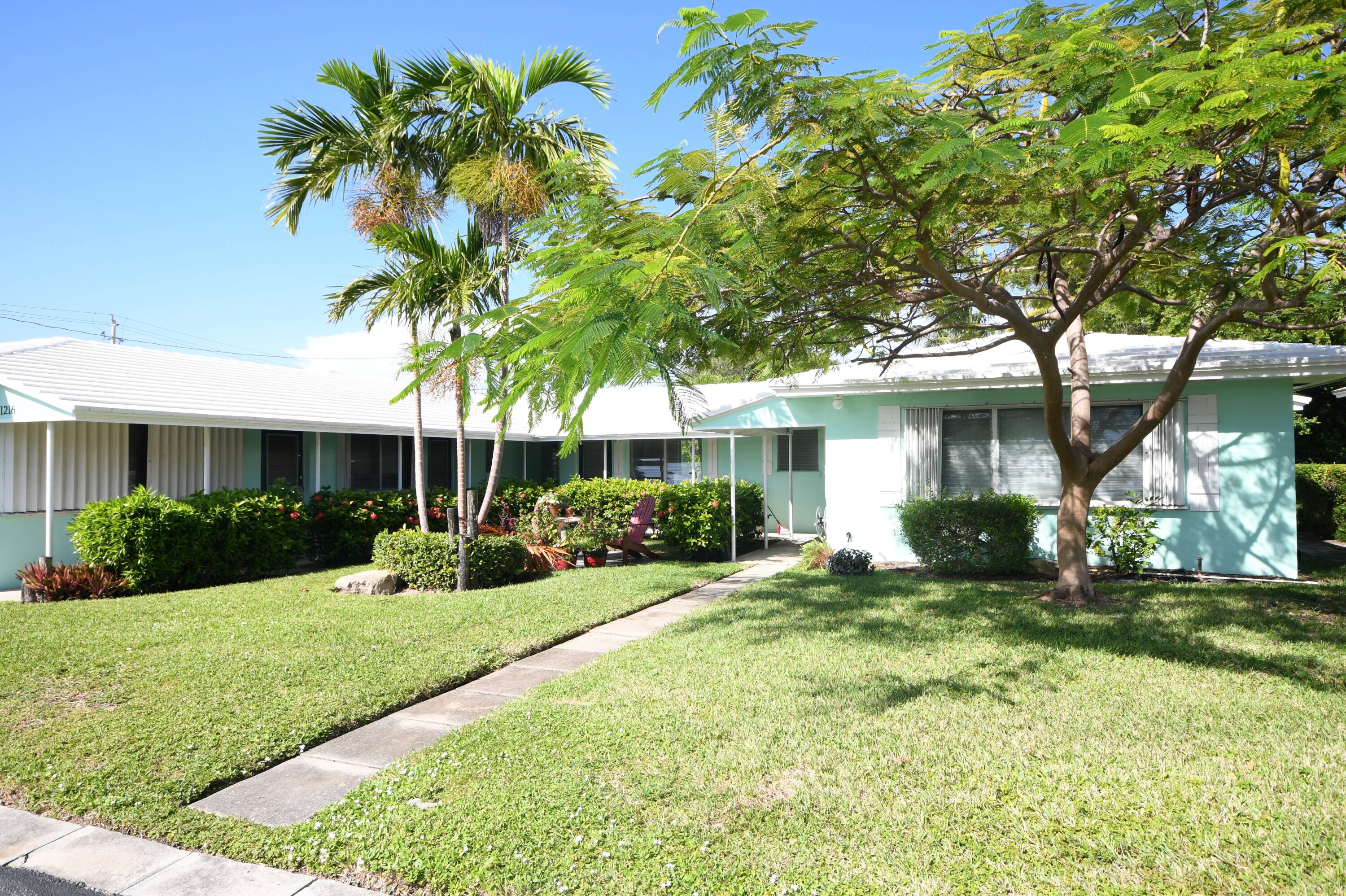 a front view of a house with a yard and potted plants