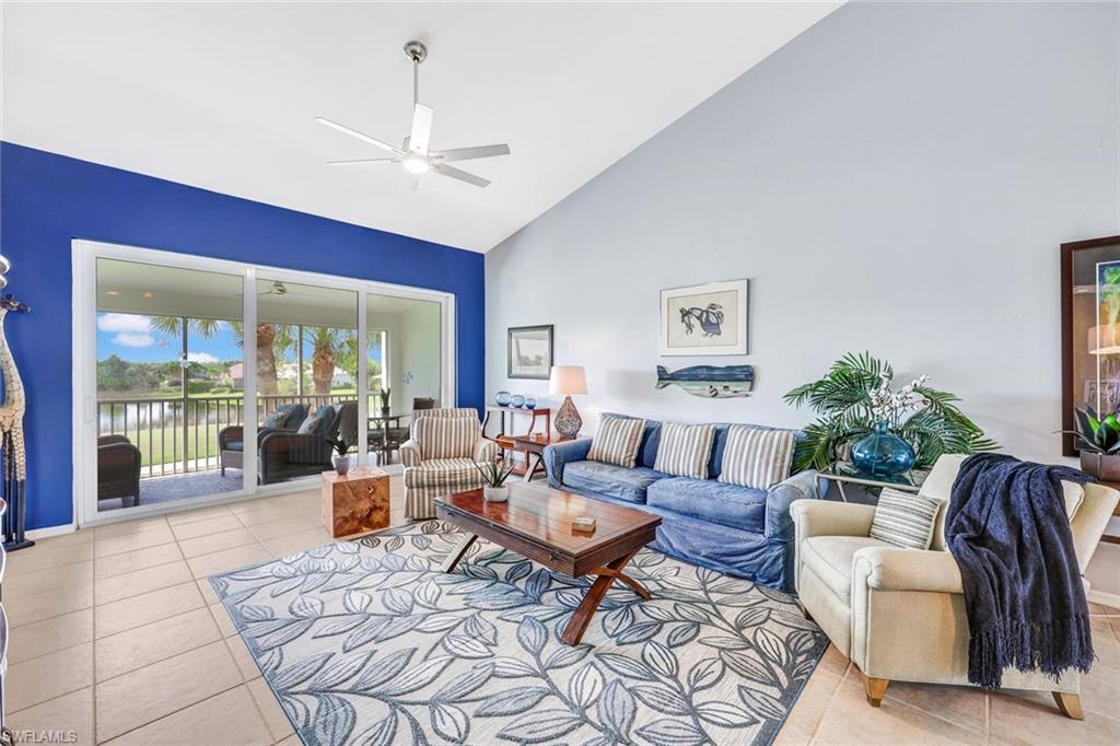 Living room with ceiling fan, light tile patterned floors, high vaulted ceiling, and a water view