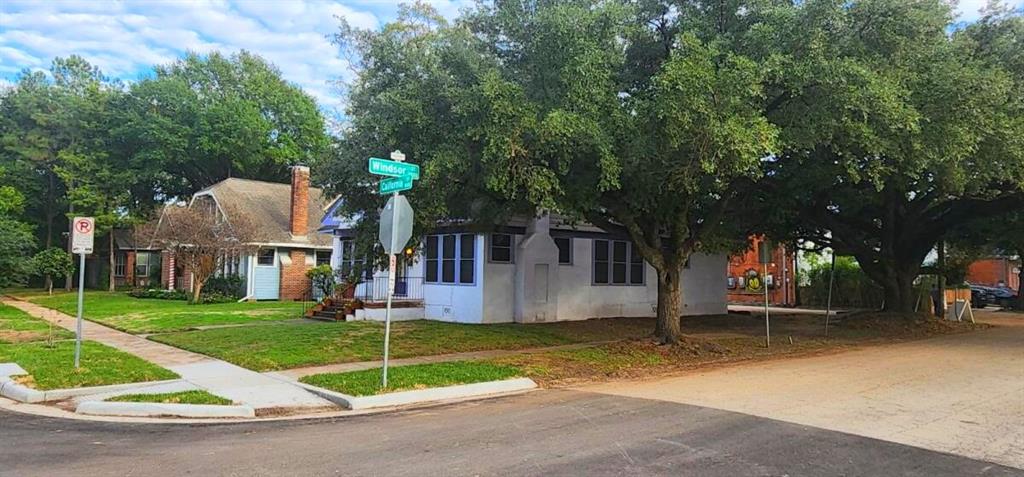 a view of a house with a yard and large trees