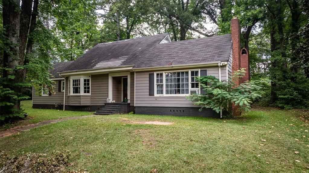 a view of a house with a garden and a tree