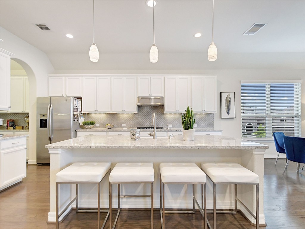 a kitchen with stainless steel appliances granite countertop a stove a sink a dining table and chairs