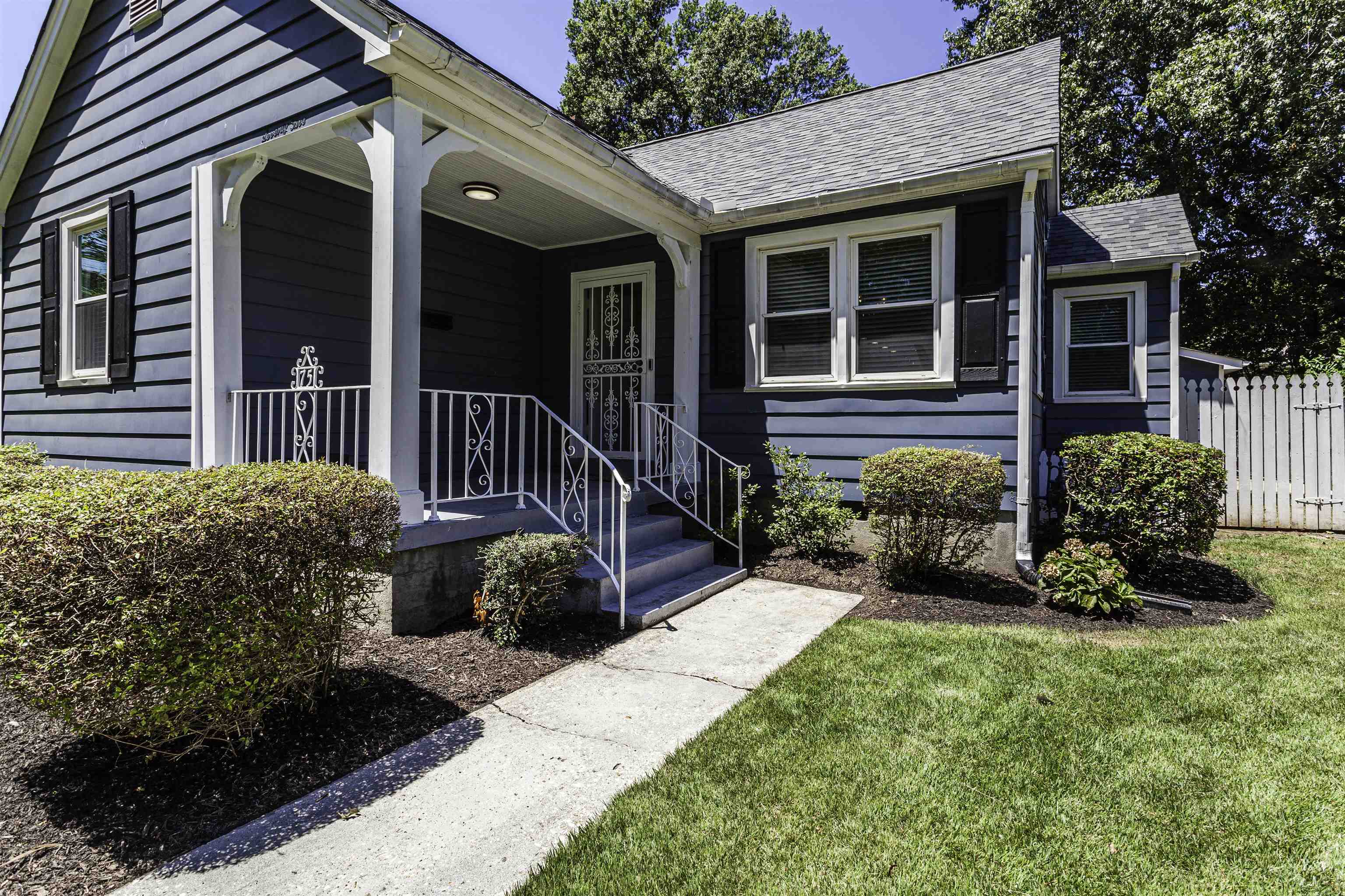 Entrance to property featuring covered porch and a lawn