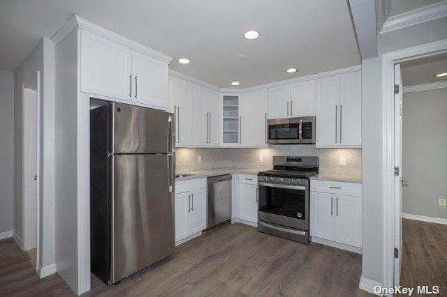 a kitchen with cabinets stainless steel appliances and wooden floor