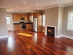 an open kitchen with kitchen island wooden floor center island and stainless steel appliances