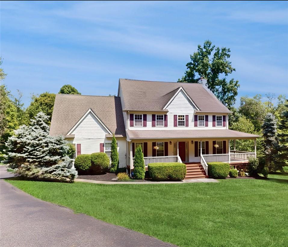 Colonial-style house featuring a front yard and covered porch