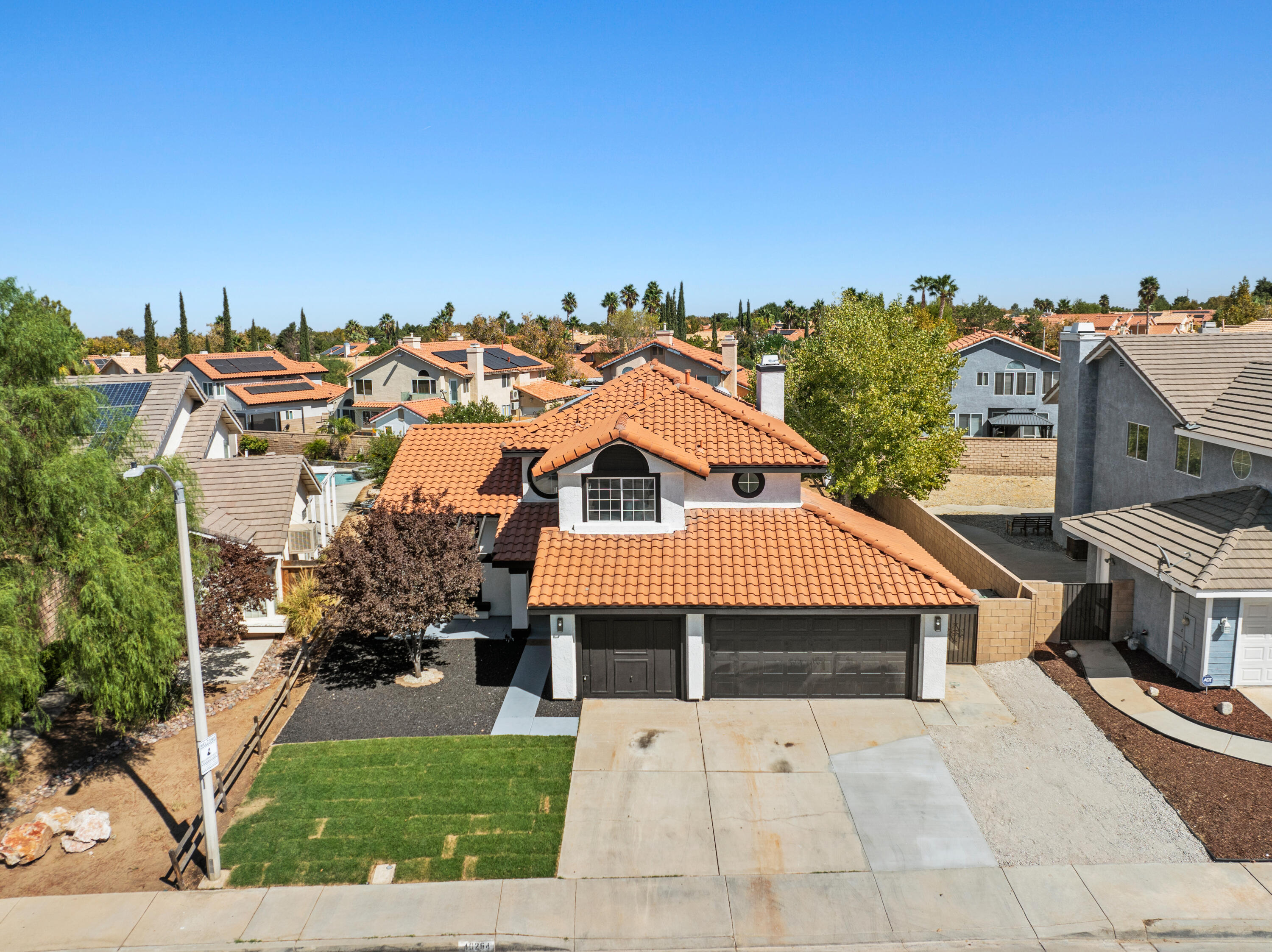 a view of a big house with a big yard plants and large trees