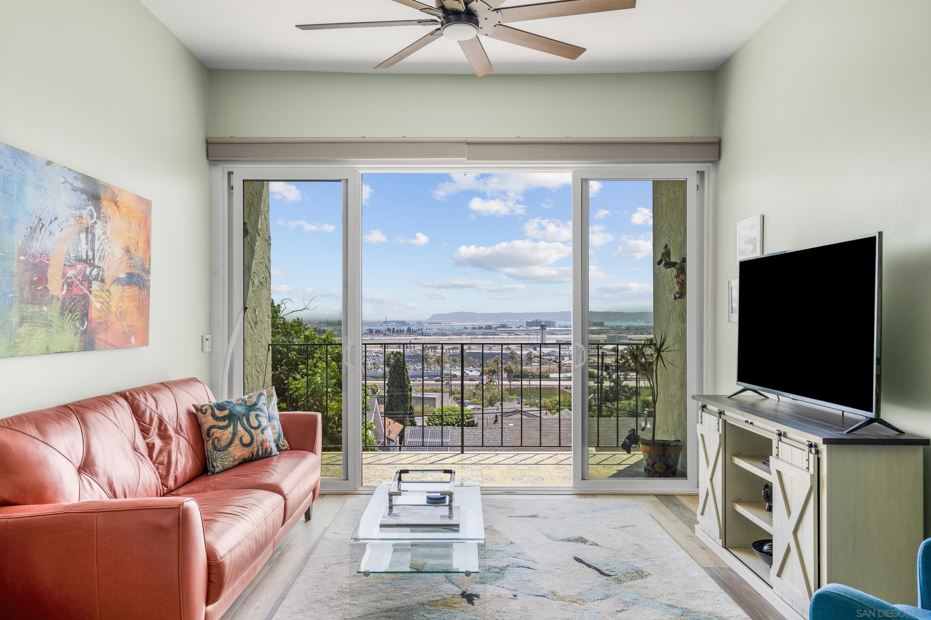 a living room with couch a flat screen tv and a floor to ceiling window