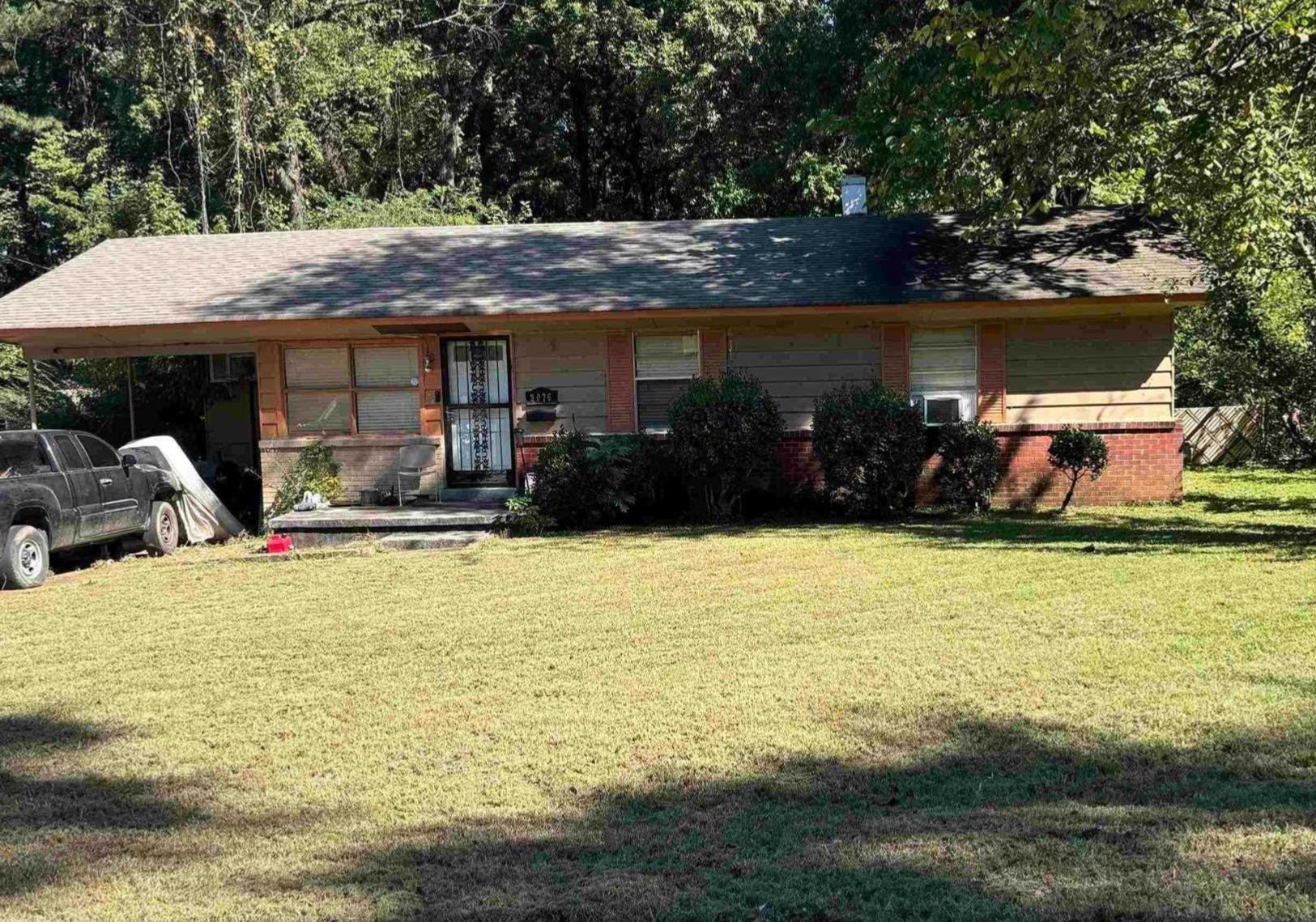 a front view of house with yard and trees in the background