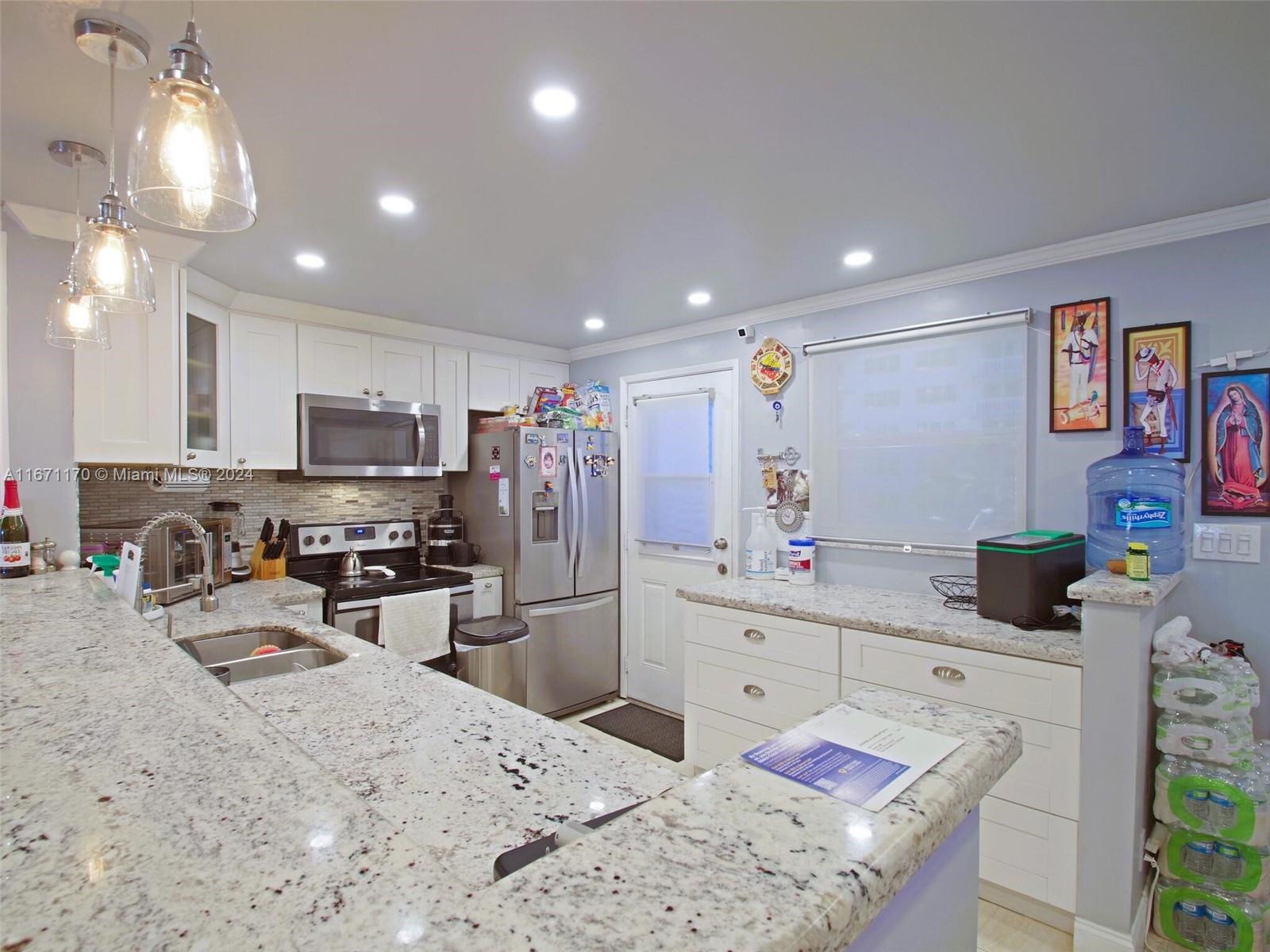 a kitchen with stainless steel appliances kitchen island granite countertop a sink refrigerator and cabinets