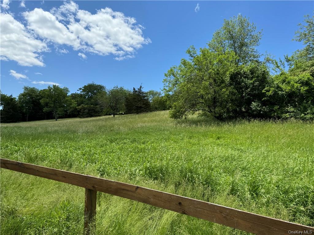 a view of a green field with wooden fence