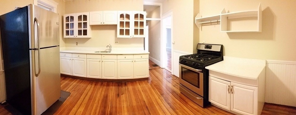 a kitchen with stainless steel appliances a stove a refrigerator and wooden floor