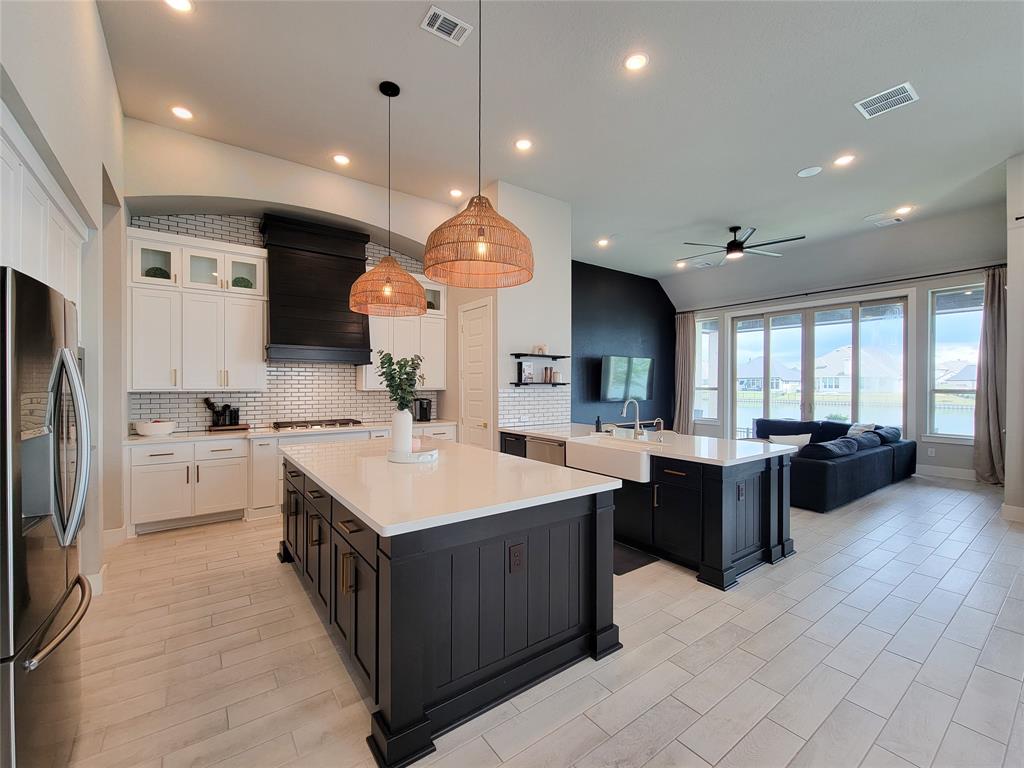 Open kitchen equipped with soft-close drawers, farmhouse sink, hooded vent, spice drawers, trash pull-out