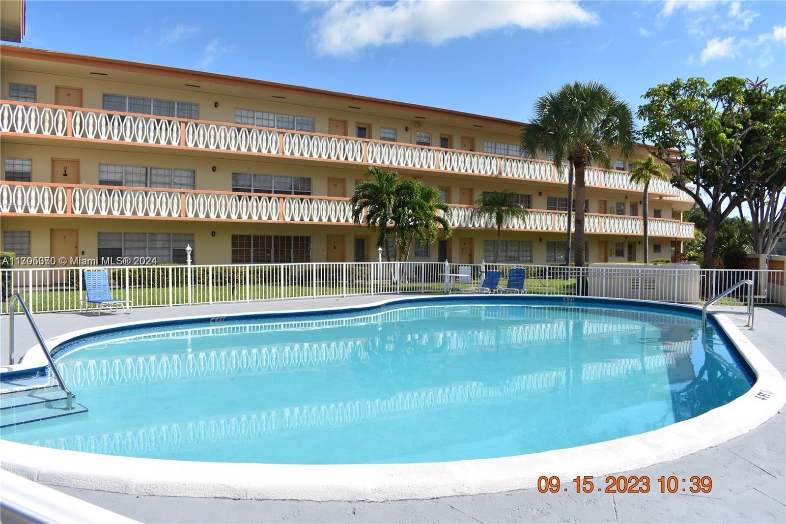 a view of a swimming pool with a lawn chairs under an umbrella