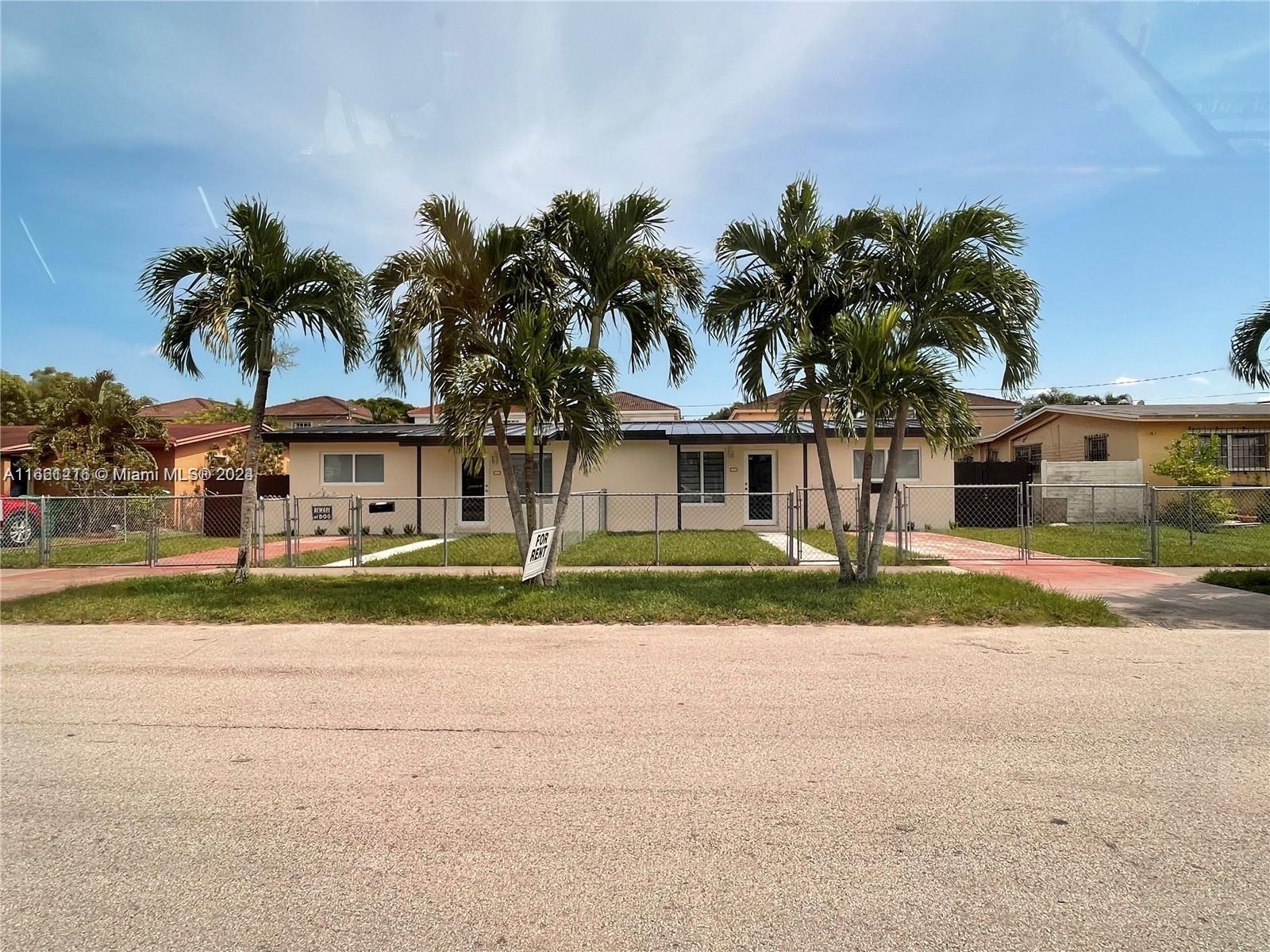 front view of house with a yard and palm trees