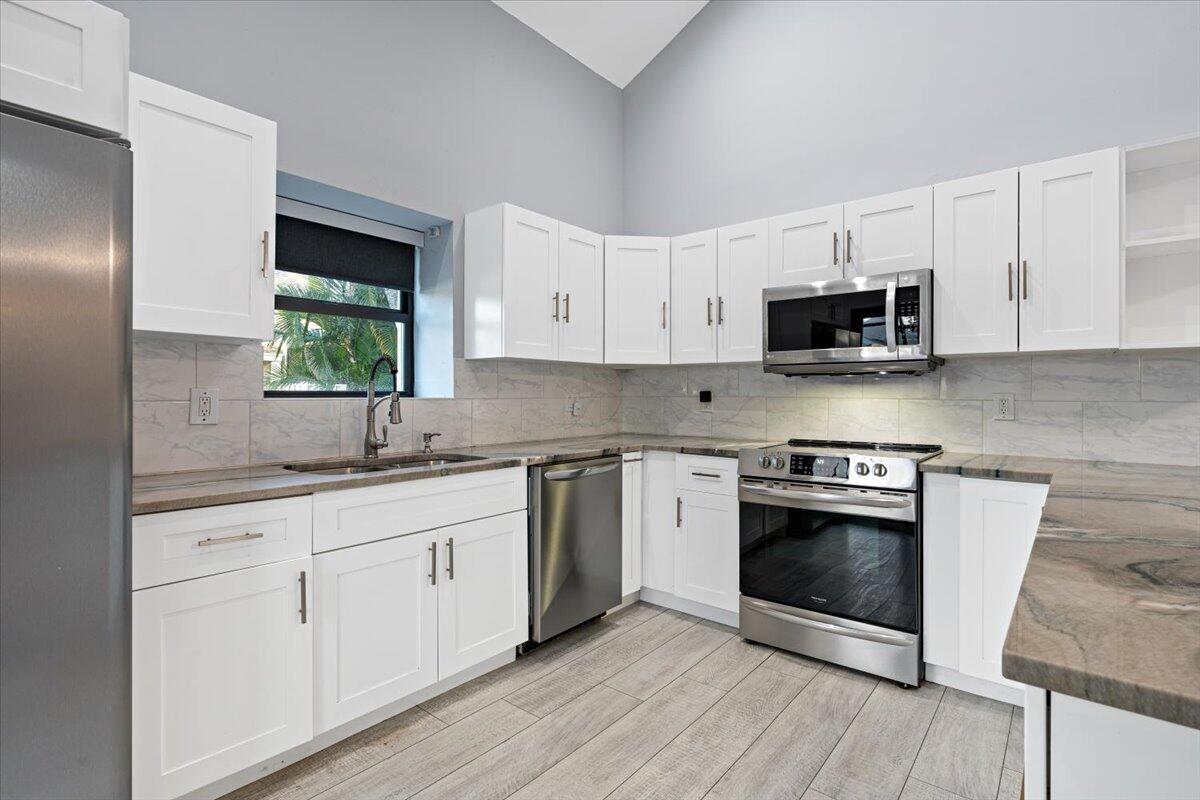 a kitchen with stainless steel appliances granite countertop a sink a stove a microwave and wooden cabinets