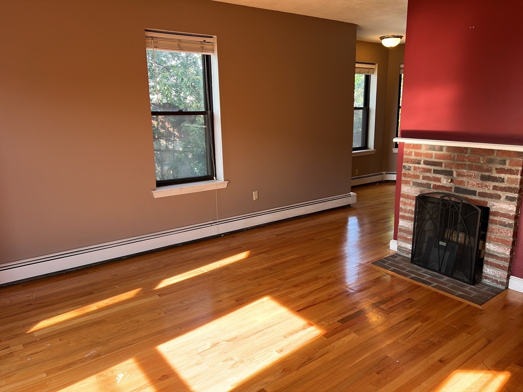 a view of a livingroom with wooden floor and a fireplace