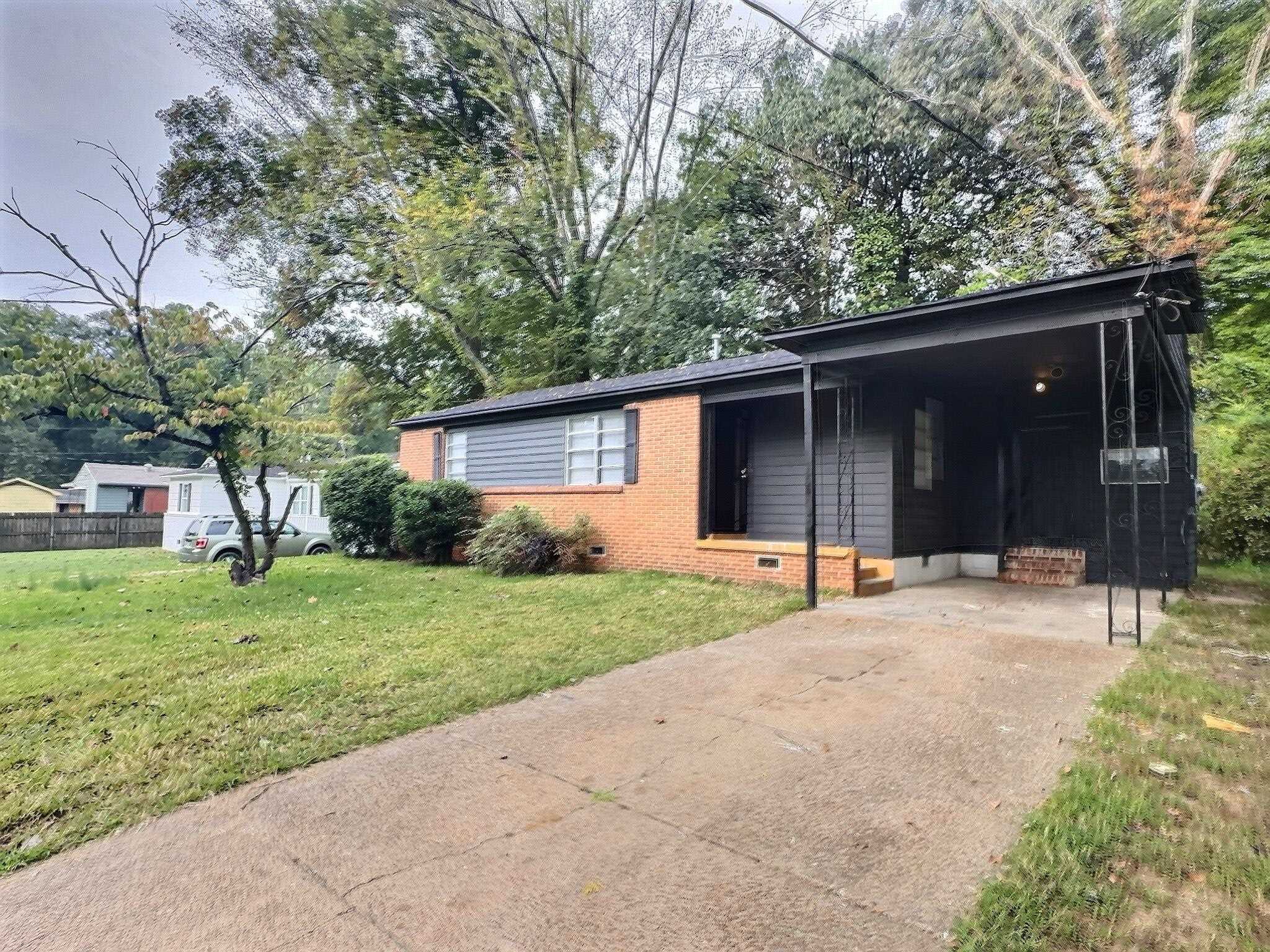 Single story home with a front lawn and a carport