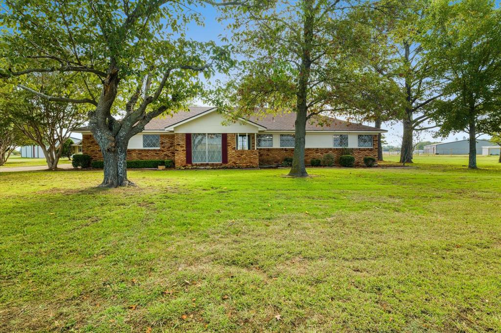 a front view of a house with a yard and trees