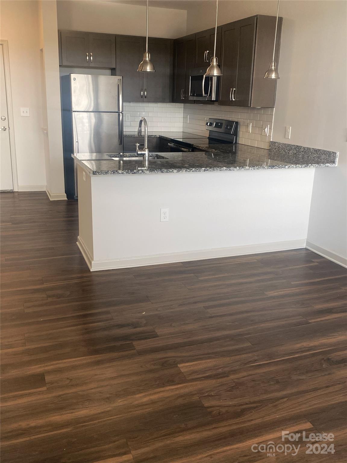 a kitchen with stainless steel appliances granite countertop a sink stove and wooden floor