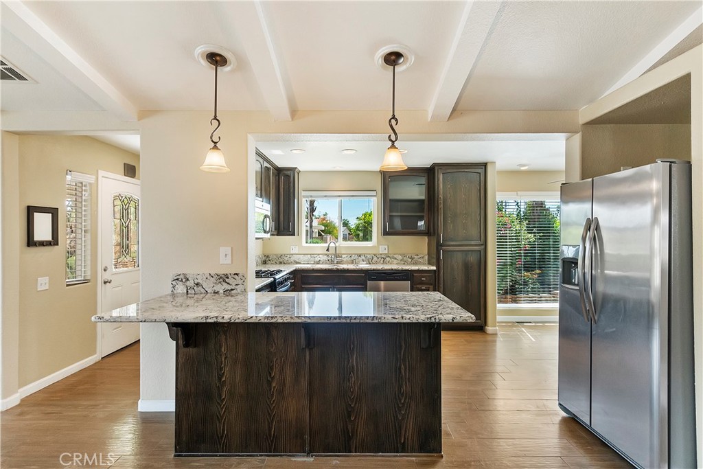 a kitchen with stainless steel appliances granite countertop a refrigerator a sink and a wooden cabinets