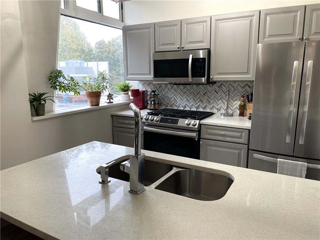 a kitchen with stainless steel appliances granite countertop a sink a microwave a refrigerator and a stove