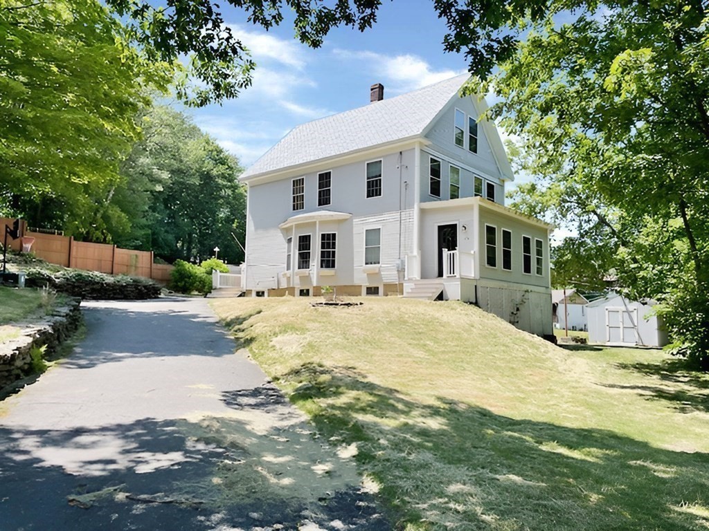 a front view of a house with a yard and trees