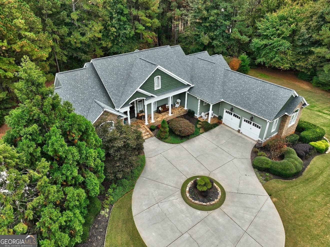 an aerial view of a house with a yard and trees all around