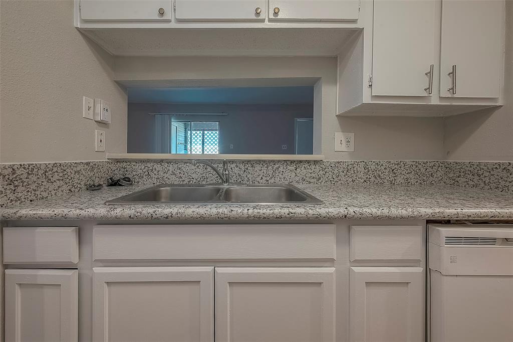 a kitchen with granite countertop white cabinets and a sink