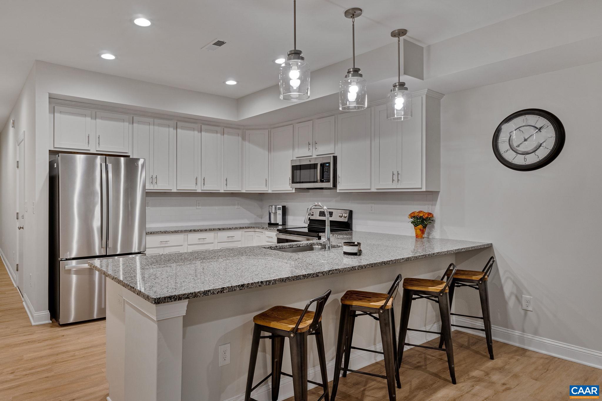 a kitchen with granite countertop a table chairs stainless steel appliances and cabinets