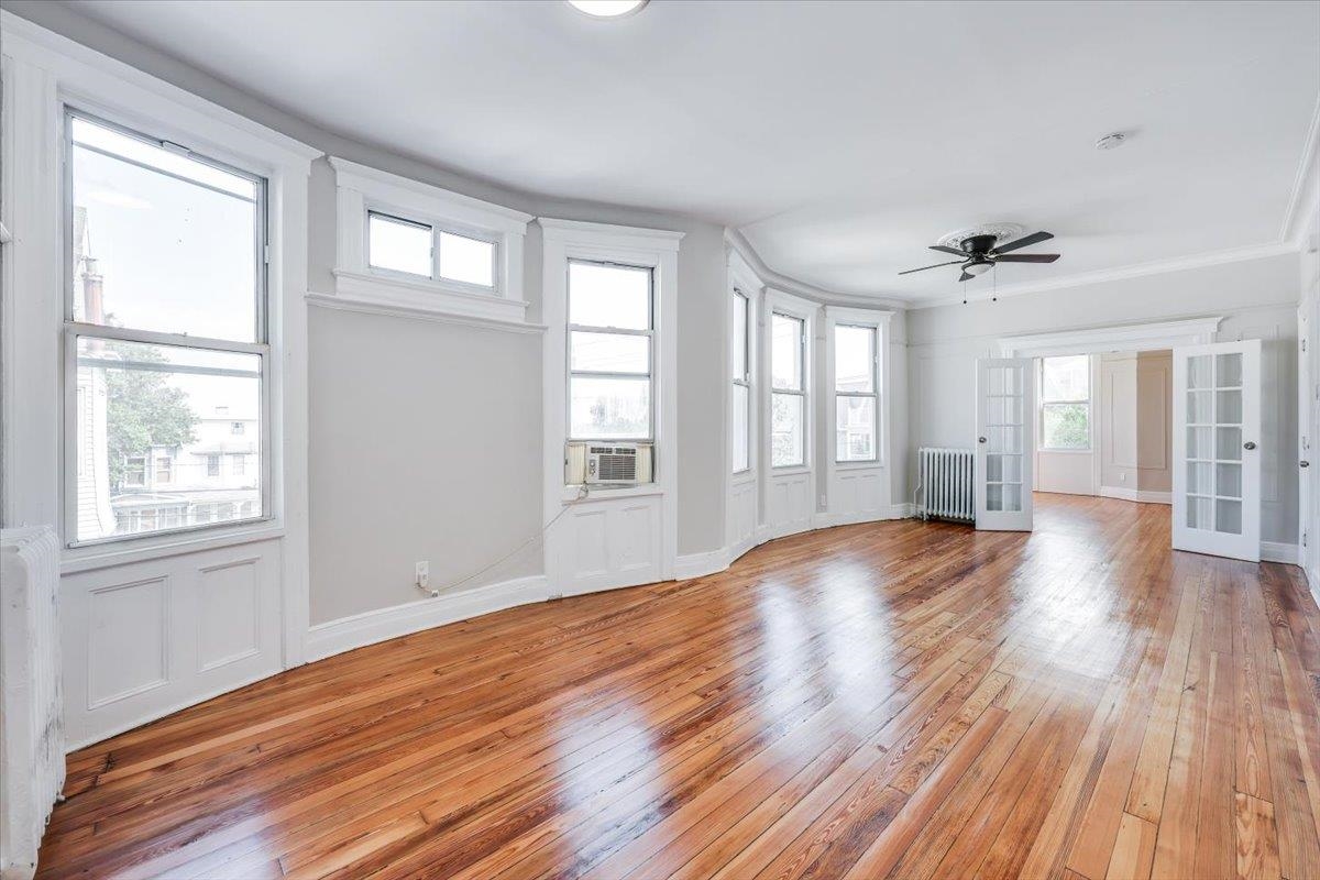 a view of an empty room with wooden floor and a window