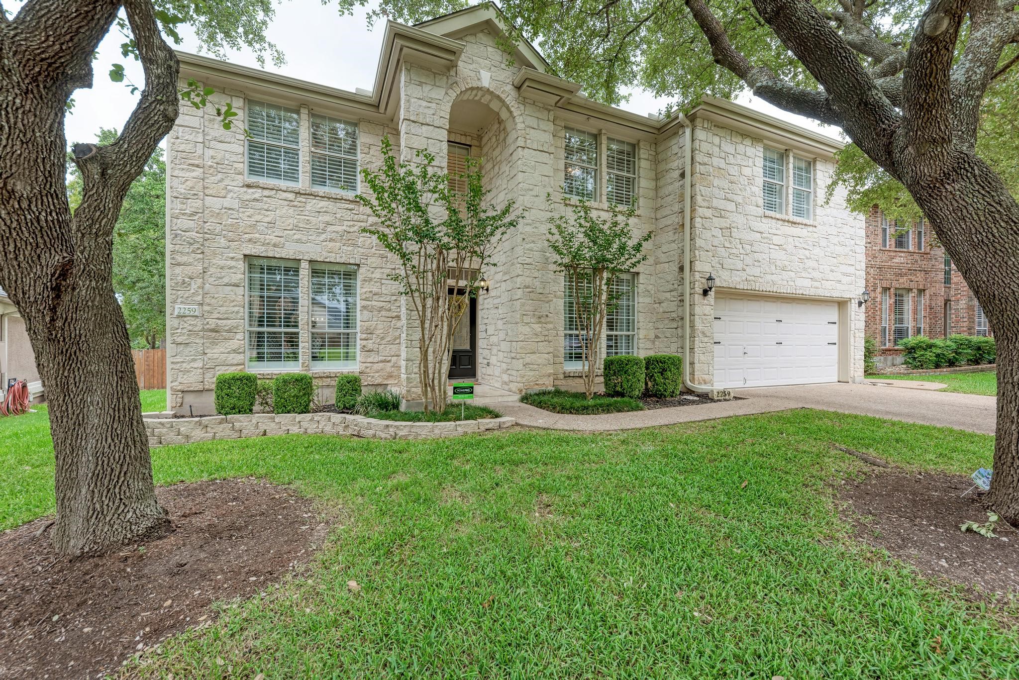 front view of a house with a yard and an trees