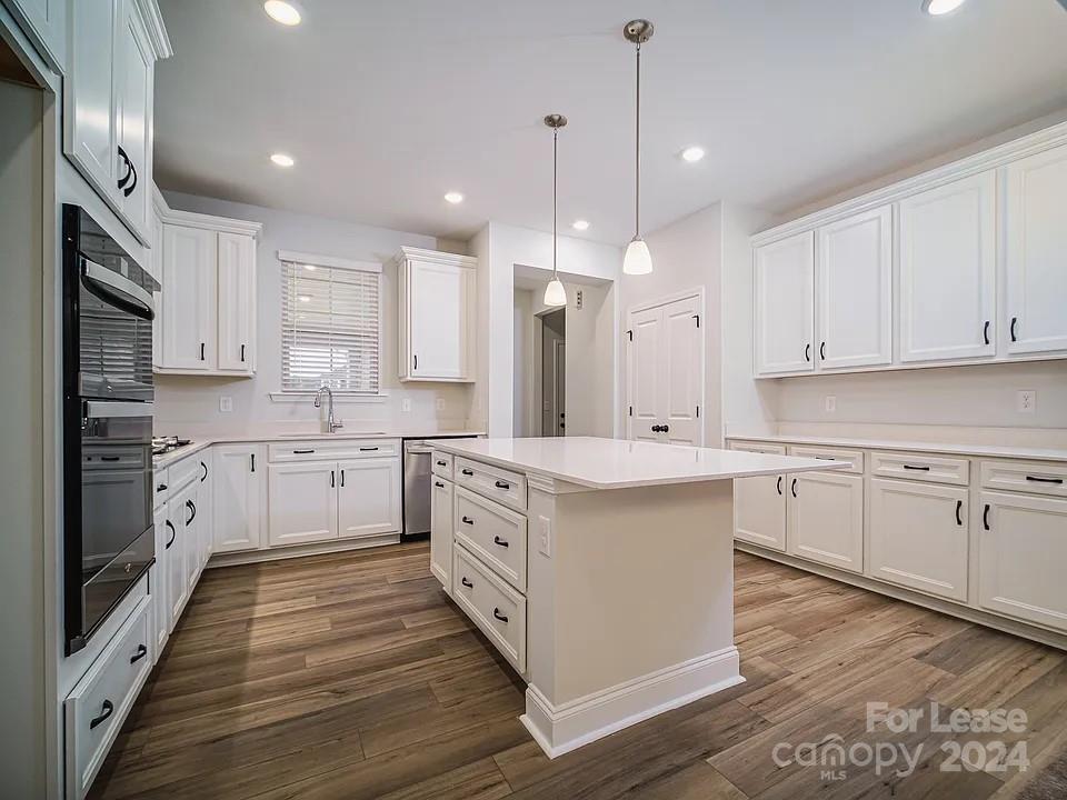 a kitchen with kitchen island granite countertop a sink cabinets and wooden floor