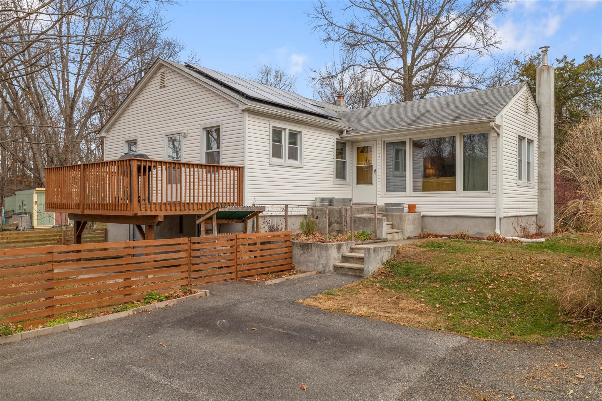 View of front of house with one of 2 decks and solar panels