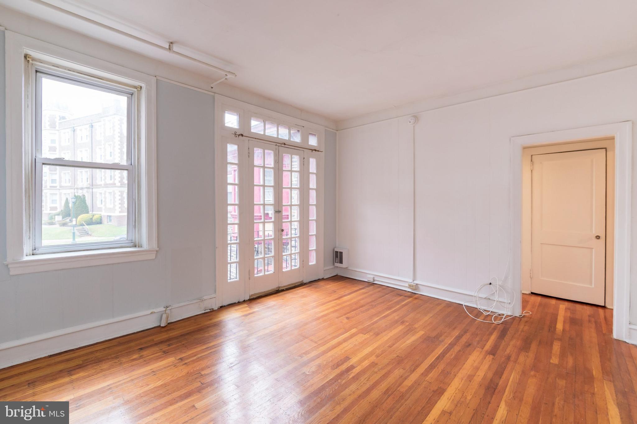 a view of an empty room with wooden floor and a window