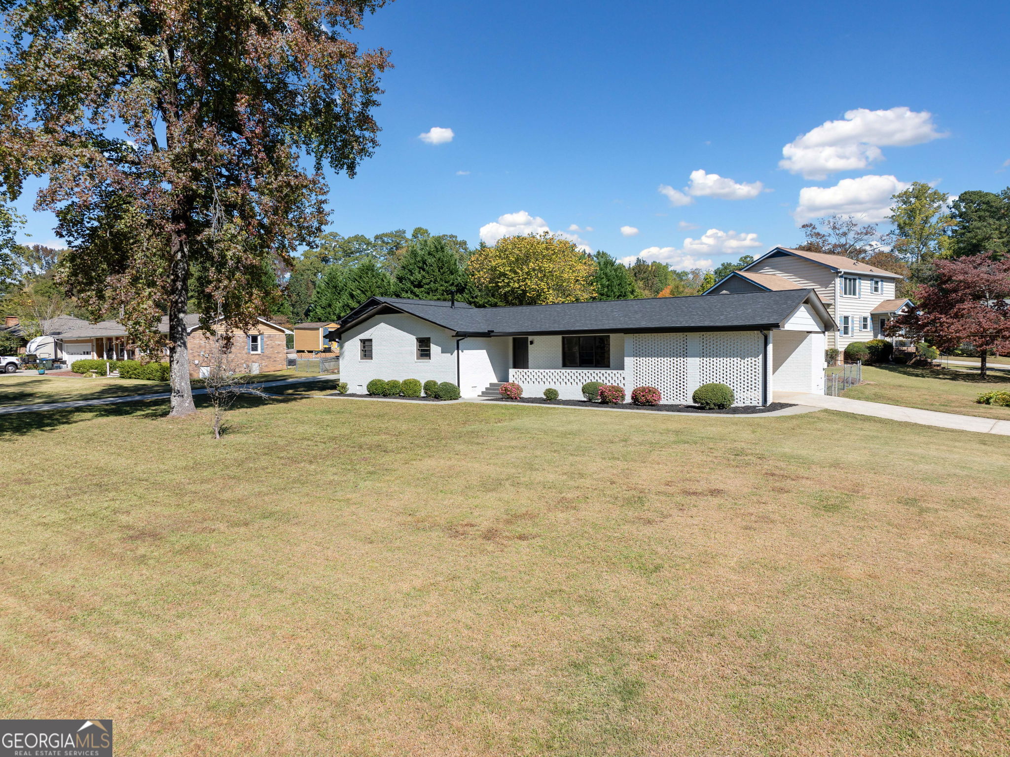 a front view of a house with a garden and tree