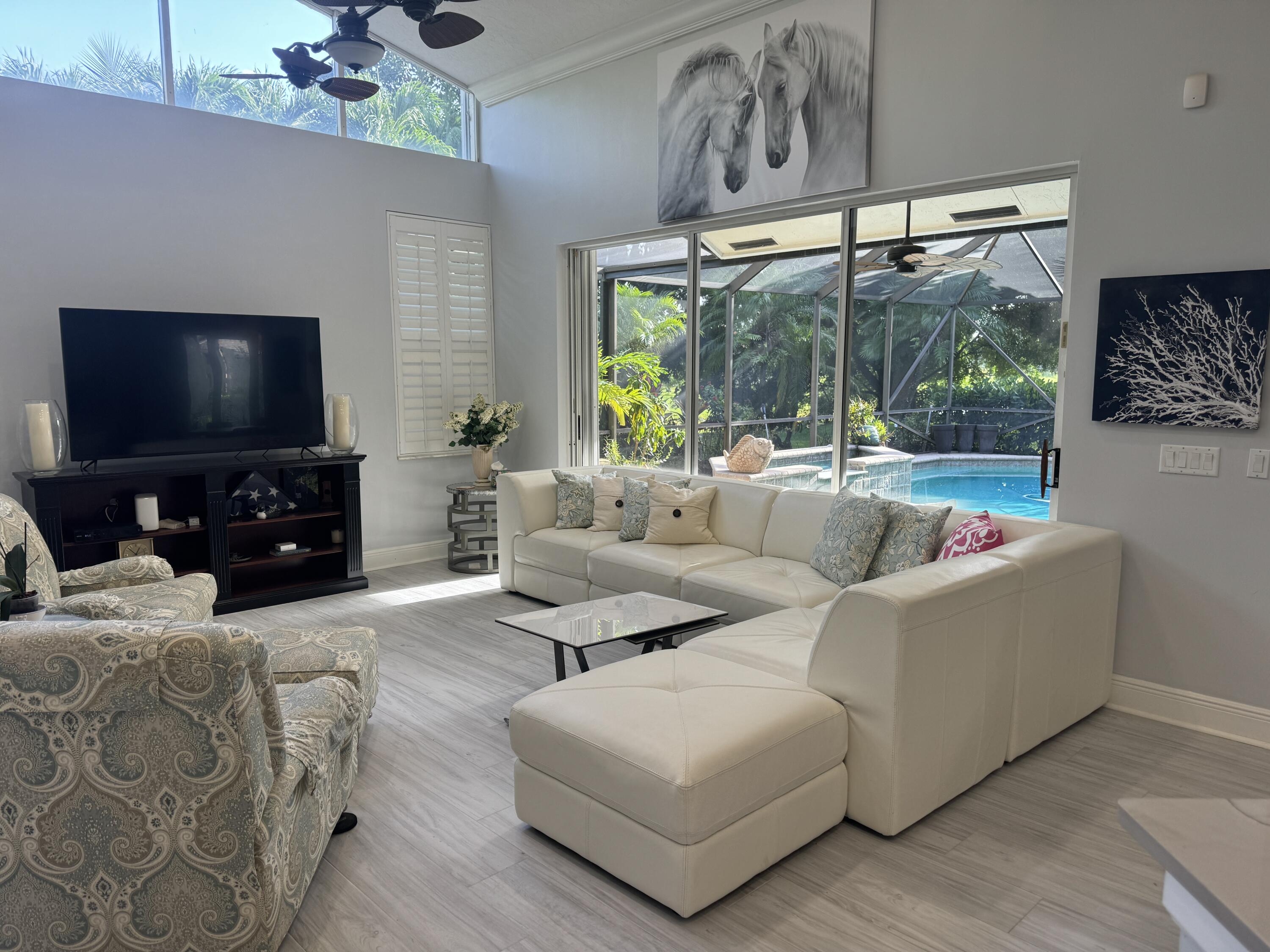 a living room with furniture a flat screen tv and a large window