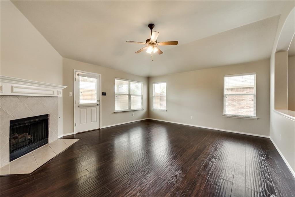 an empty room with wooden floor fireplace and windows