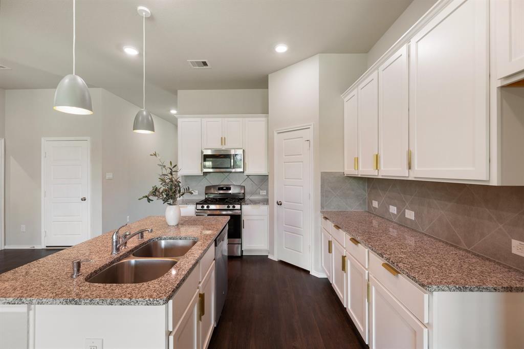 a kitchen with kitchen island granite countertop a sink and refrigerator