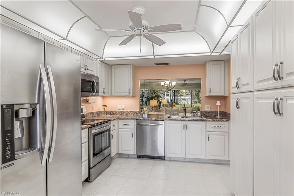 a kitchen with stainless steel appliances granite countertop a sink a stove a refrigerator and cabinetry