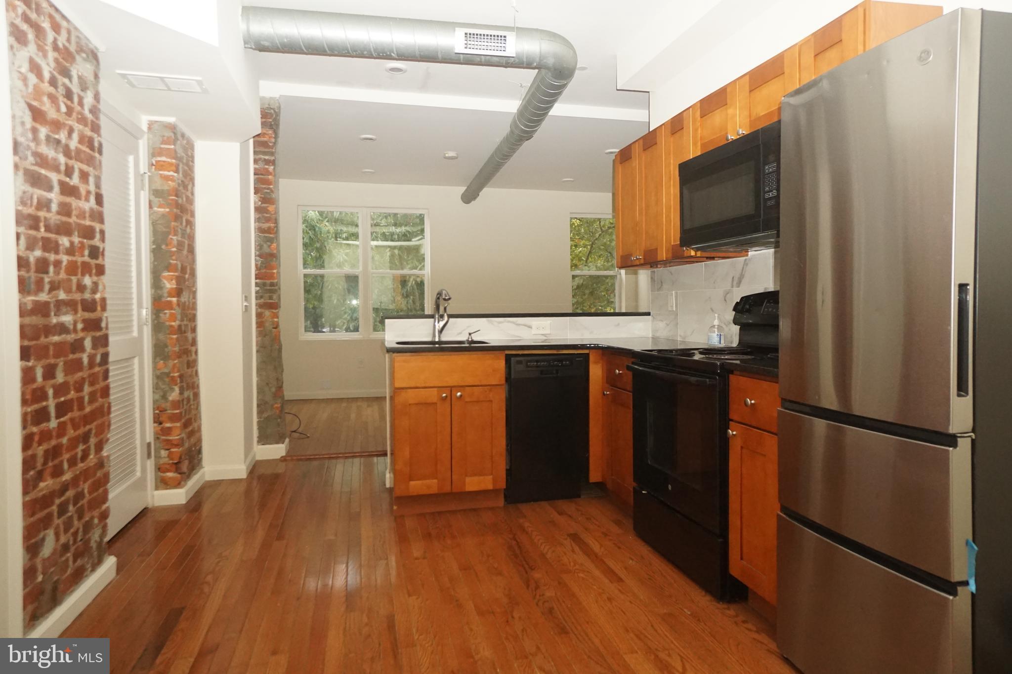 a kitchen with stainless steel appliances granite countertop a refrigerator a sink and wooden cabinets