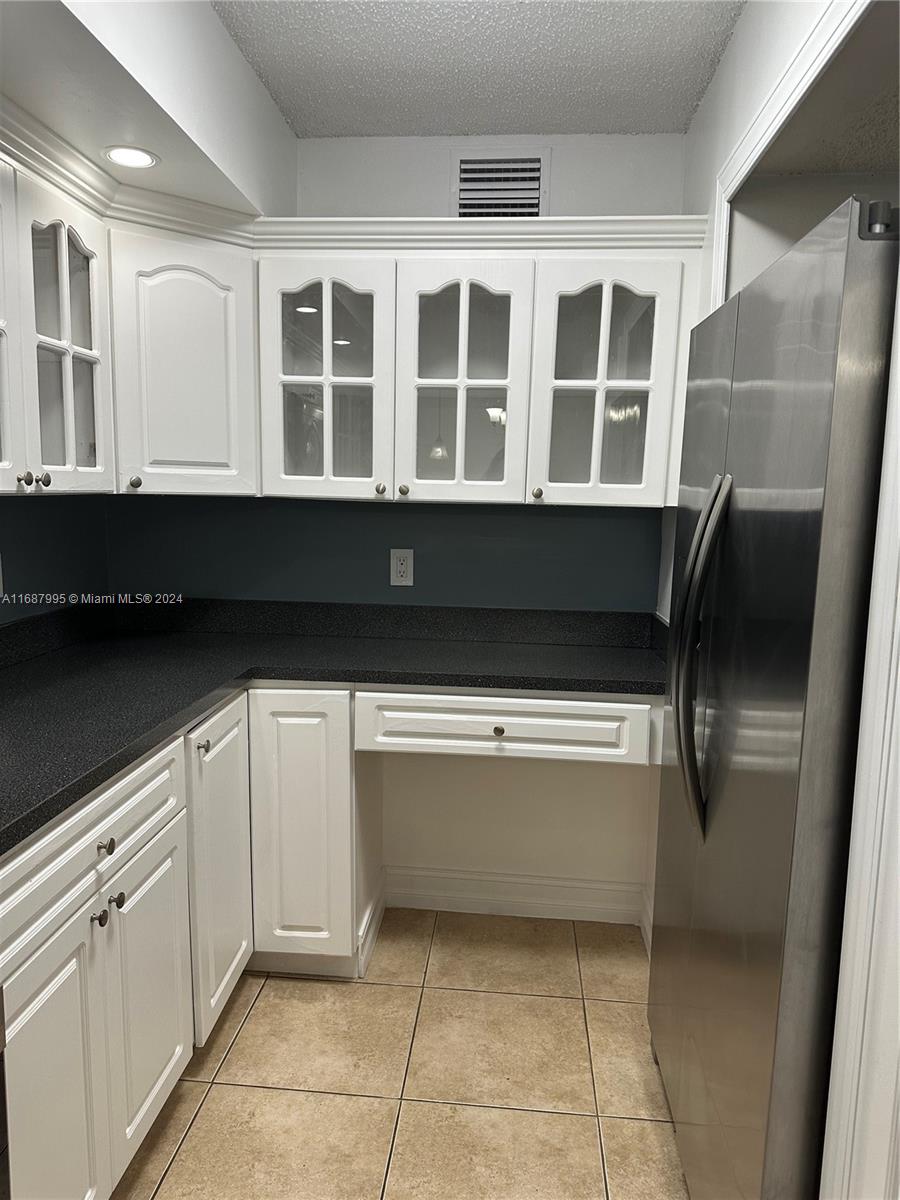 a kitchen with a refrigerator and white cabinets