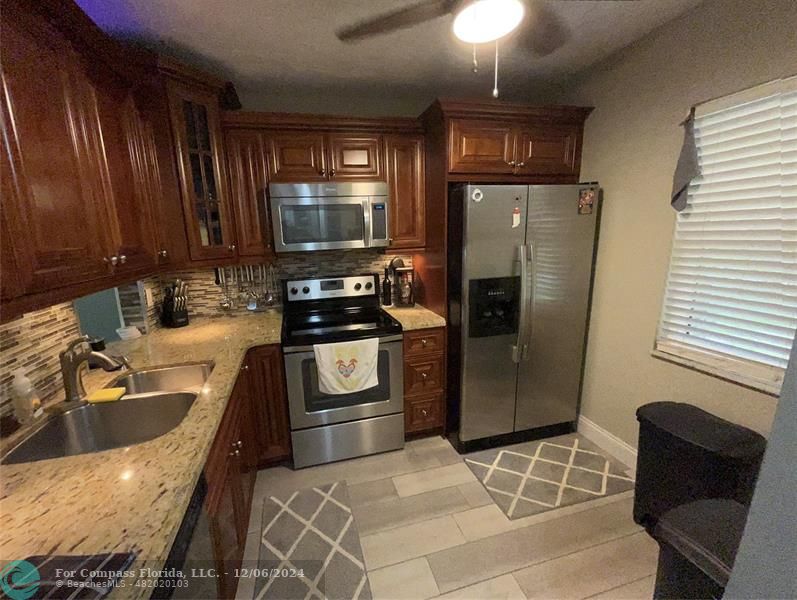 a kitchen with stainless steel appliances granite countertop a refrigerator stove and sink