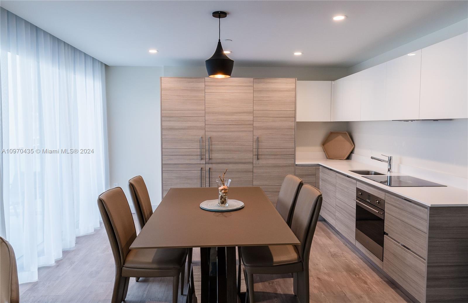 a kitchen with stainless steel appliances a dining table chairs and a refrigerator