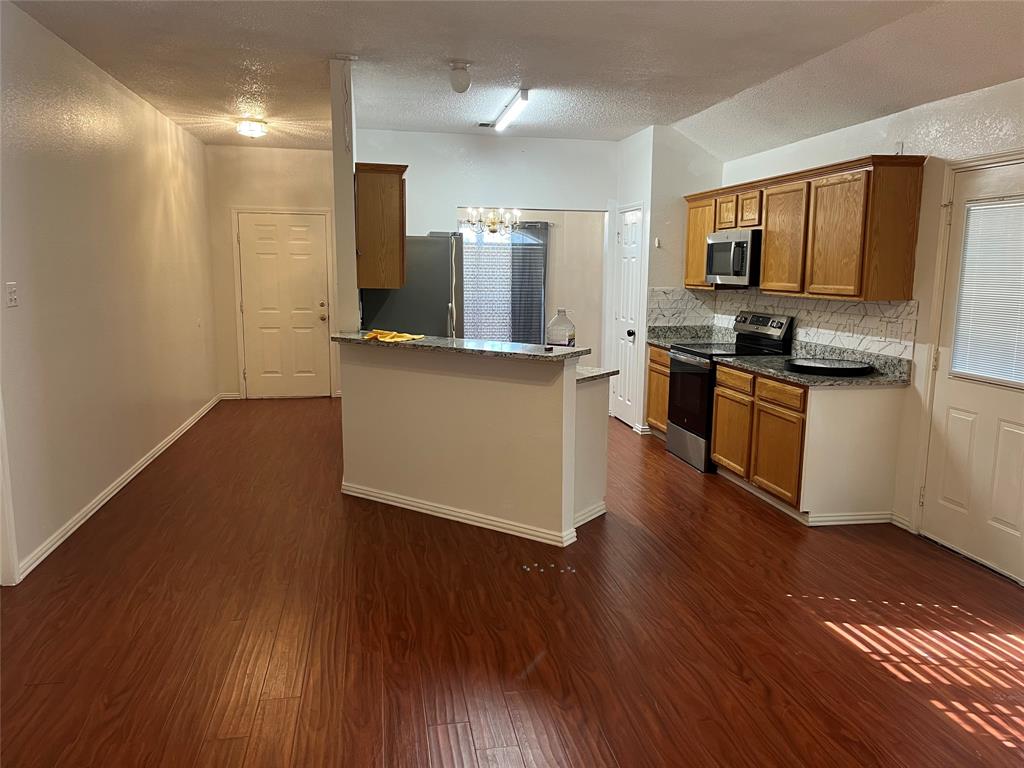 a kitchen with stainless steel appliances wooden floors and view living room